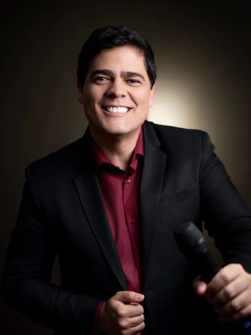 Matheus Pissolatti sorrindo, vestindo blazer preto