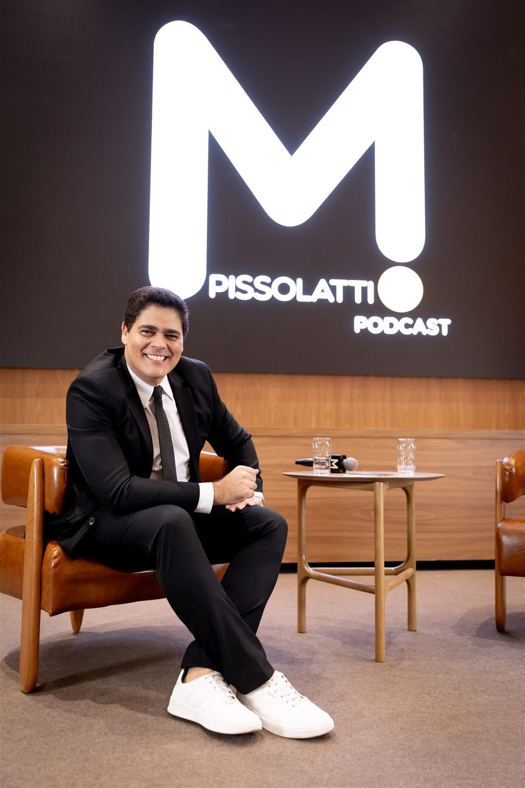 Matheus Pissolatti sentado em estúdio, sob o letreiro do podcast M. Pissolatti